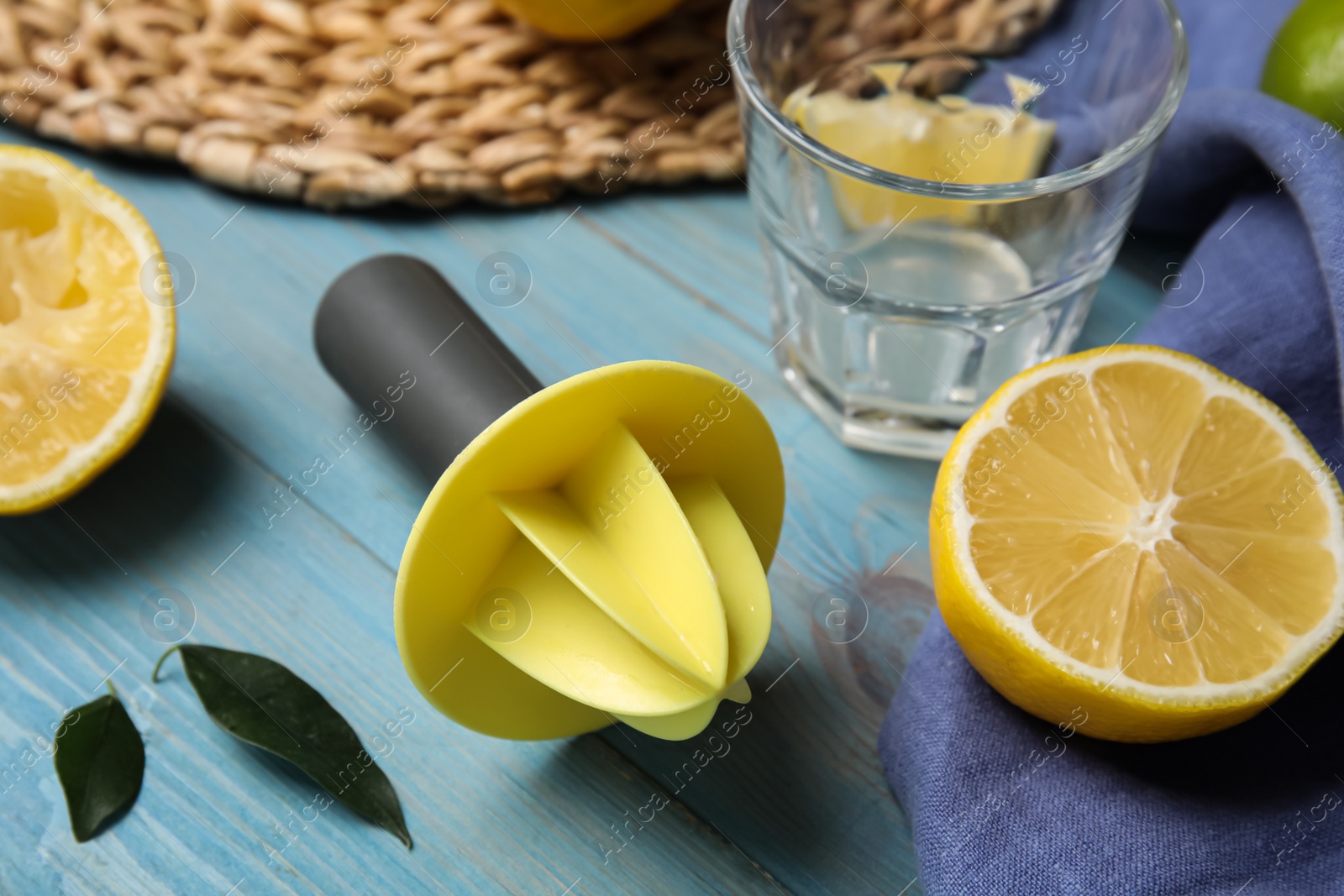 Photo of Squeezer and fresh lemon on light blue wooden table
