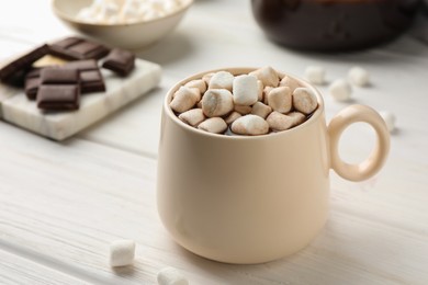 Photo of Cup of aromatic hot chocolate with marshmallows on white wooden table, closeup