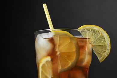Photo of Glass of delicious iced tea against black background, closeup