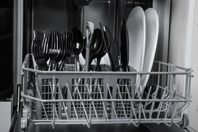 Photo of Open modern dishwasher with clean tableware, closeup