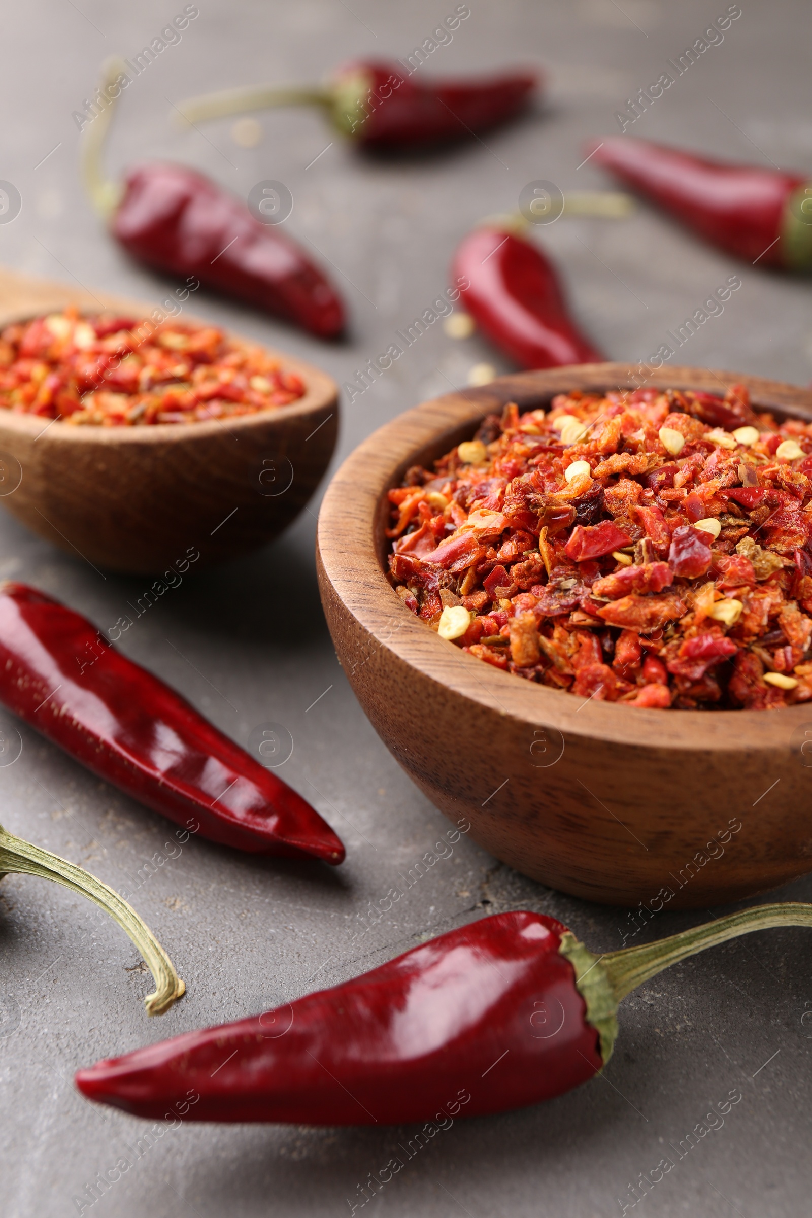 Photo of Chili pepper flakes and pods on grey table, closeup