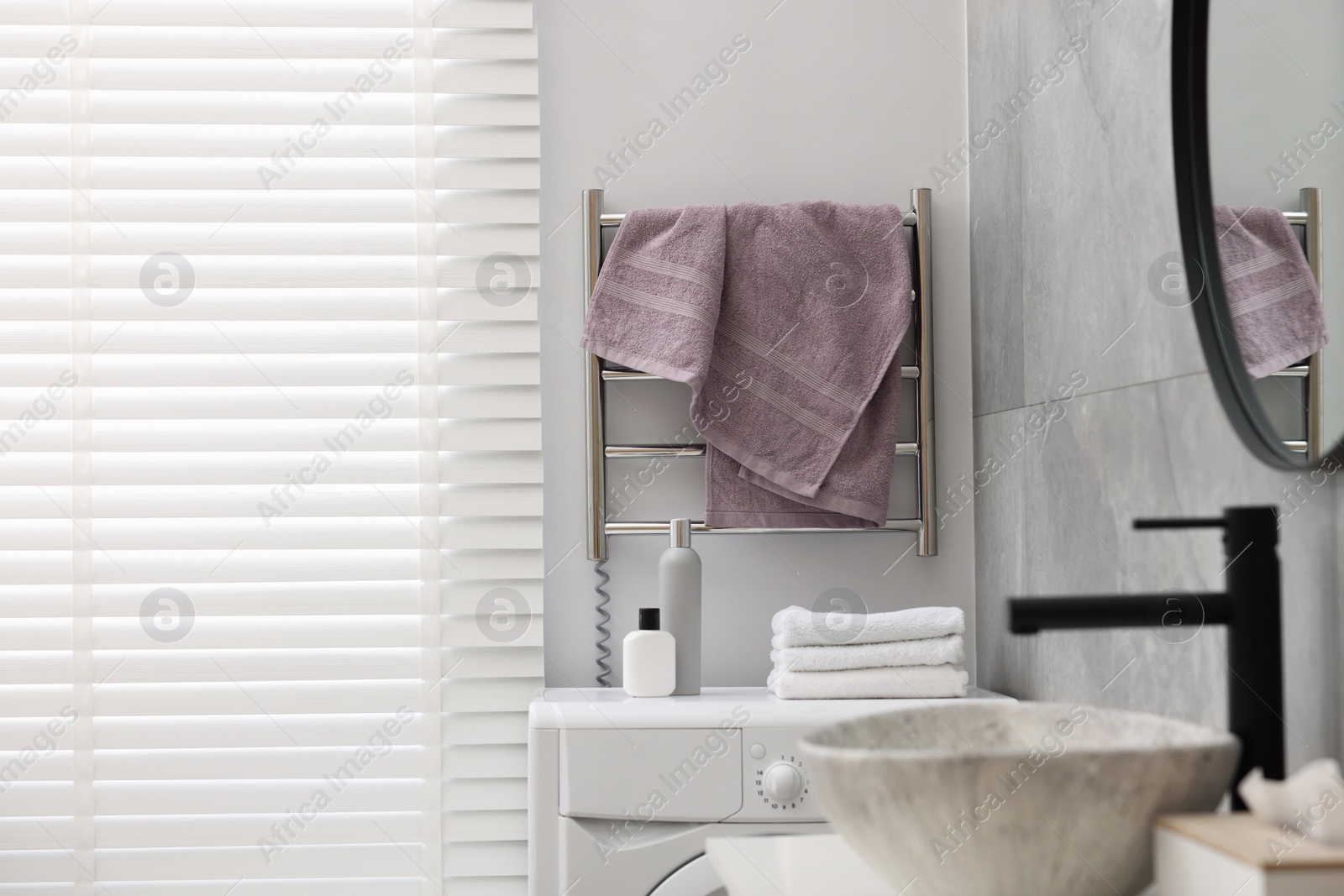 Photo of Clean terry towel on heated rail in bathroom