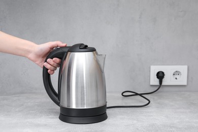 Photo of Woman with electric kettle in kitchen, closeup. Space for text