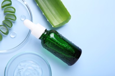 Photo of Cut aloe vera, bottle and cosmetic gel on light blue background, flat lay. Space for text