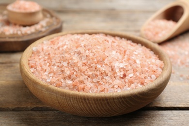 Pink himalayan salt in bowl on wooden table, closeup