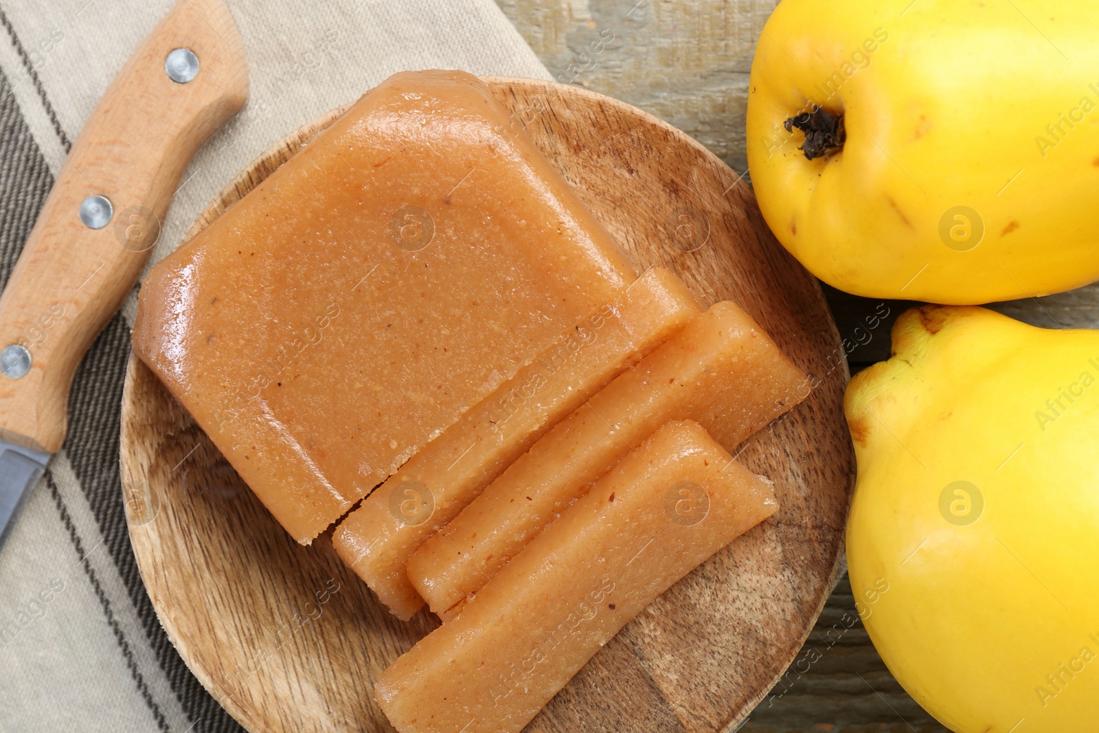 Photo of Tasty sweet quince paste, fresh fruits and knife on wooden table, flat lay