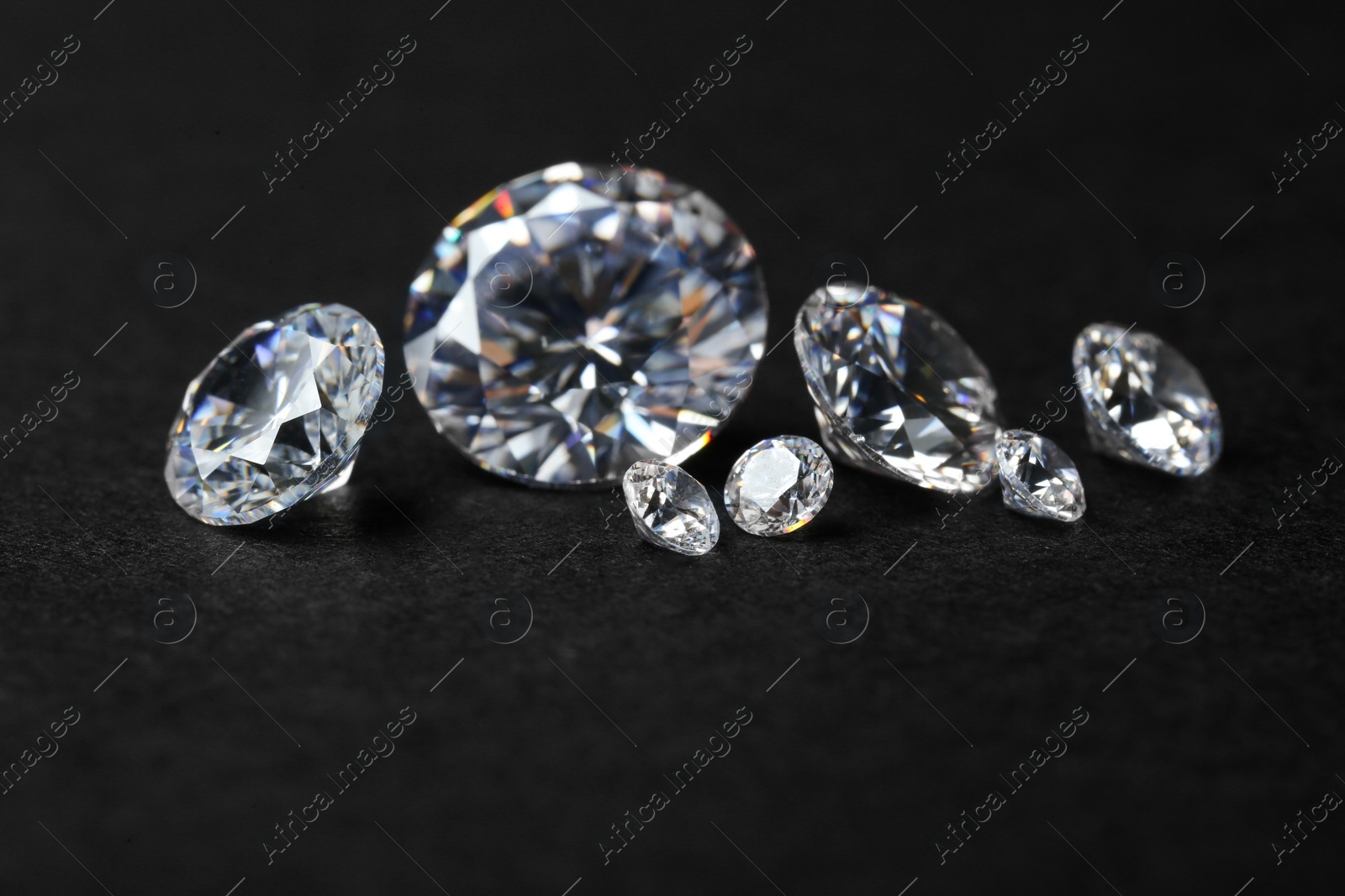 Photo of Many beautiful shiny diamonds on black background