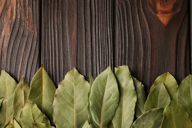 Photo of Aromatic bay leaves on wooden table, top view. Space for text