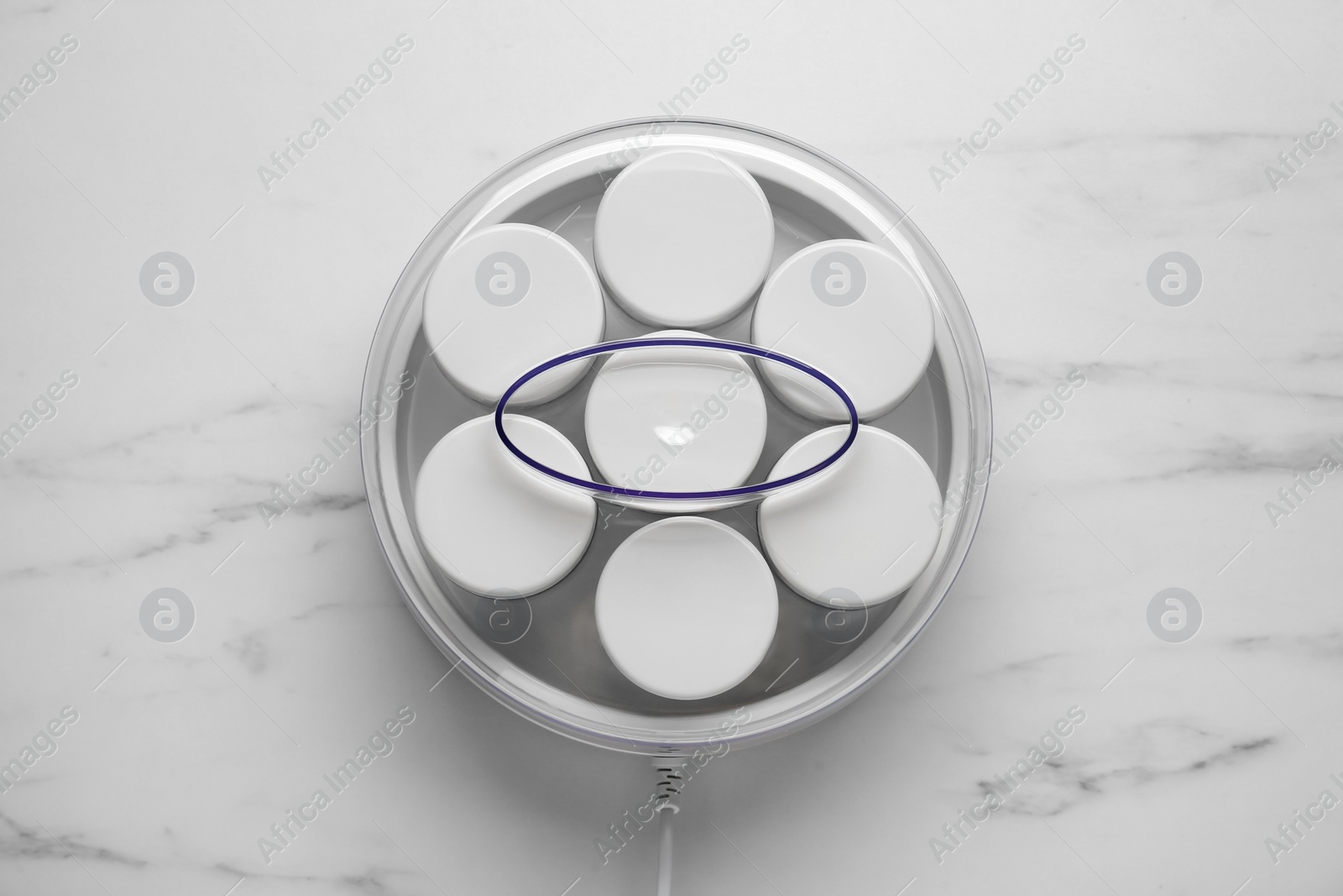 Photo of Modern yogurt maker with jars on white marble table, top view