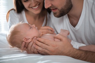 Photo of Happy couple with their newborn baby at home, closeup