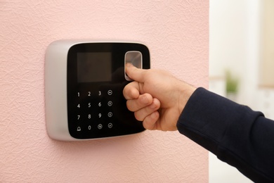 Man scanning fingerprint on alarm system at home, closeup