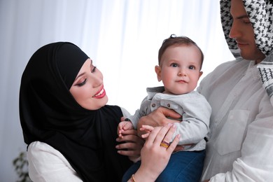 Happy Muslim family with little son indoors