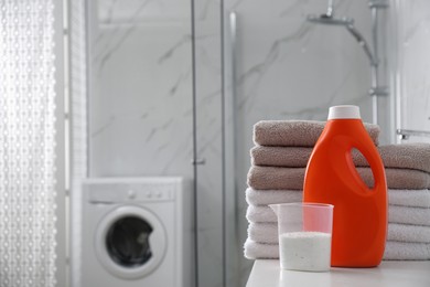 Photo of Stack of folded towels and detergents on white table in bathroom, space for text