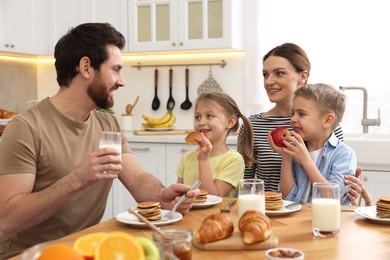 Happy family having fun during breakfast at table in kitchen