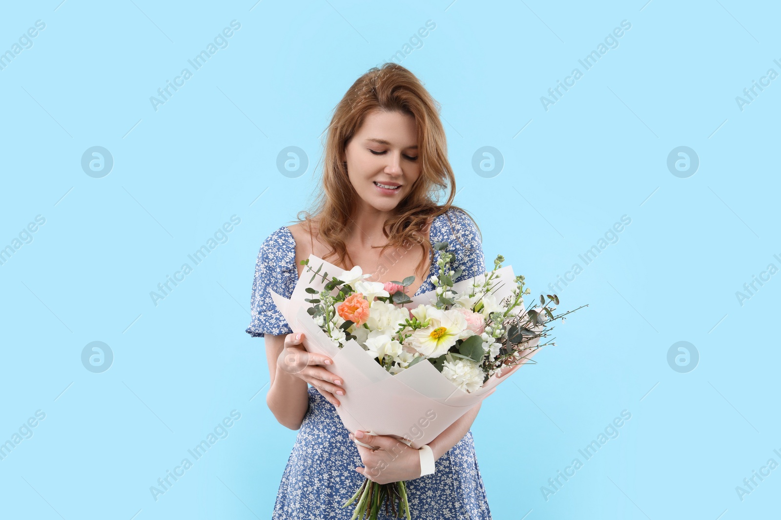 Photo of Beautiful woman with bouquet of flowers on light blue background