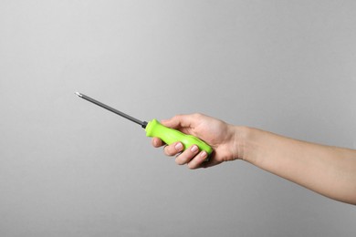 Photo of Woman holding screwdriver on grey background, closeup