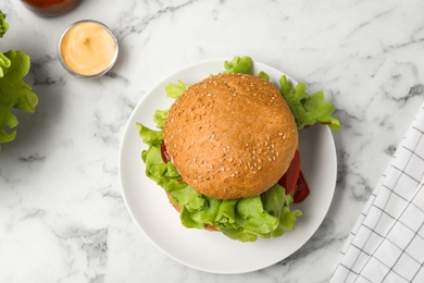 Photo of Tasty burger with lettuce and tomato in plate on table, top view