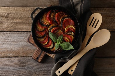 Photo of Delicious ratatouille, spoon and spatula on wooden table, flat lay