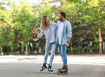 Young happy couple roller skating on city street