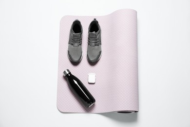 Photo of Exercise mat, bottle of water, wireless earphones and shoes on light grey background, top view