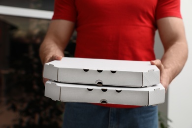 Courier with pizza boxes on blurred background, closeup