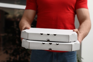 Photo of Courier with pizza boxes on blurred background, closeup