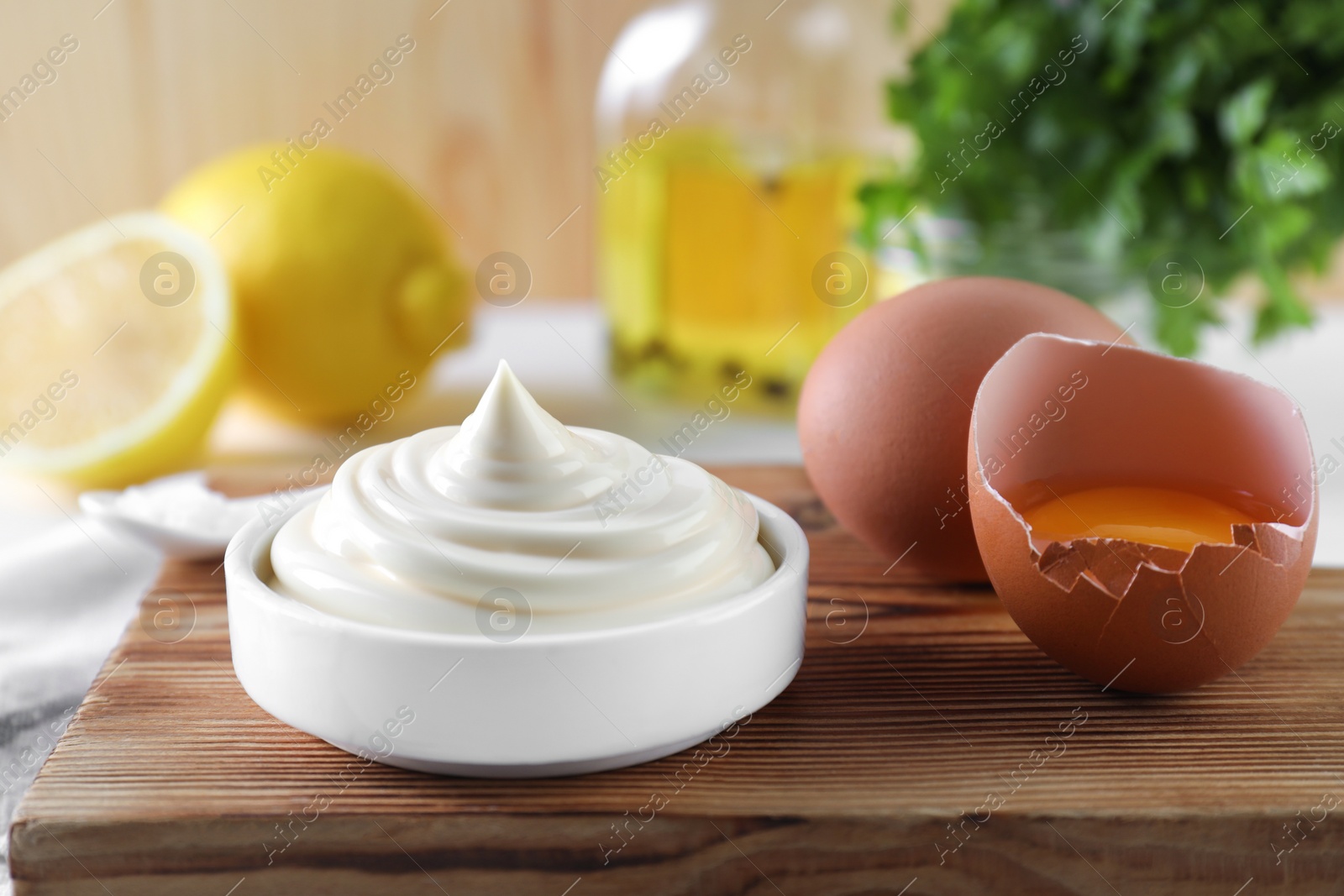 Photo of Fresh mayonnaise sauce in bowl and ingredients on table, closeup