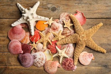 Photo of Beautiful sea stars and shells on wooden background, flat lay