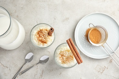 Photo of Creamy rice pudding with cinnamon in glasses served on grey table, top view