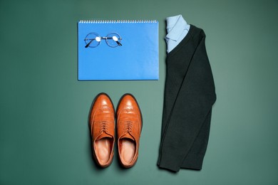 Photo of Stylish school uniform, glasses and notebook on green background, flat lay