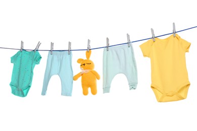 Photo of Colorful baby clothes and toy drying on laundry line against white background