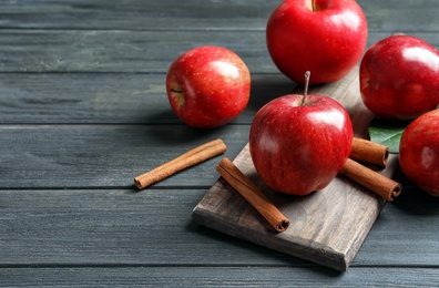 Photo of Fresh apples and cinnamon sticks on wooden table