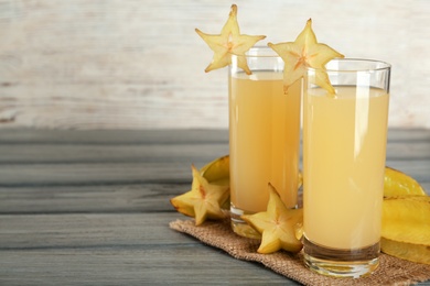 Delicious carambola juice and fresh fruits on grey wooden table. Space for text