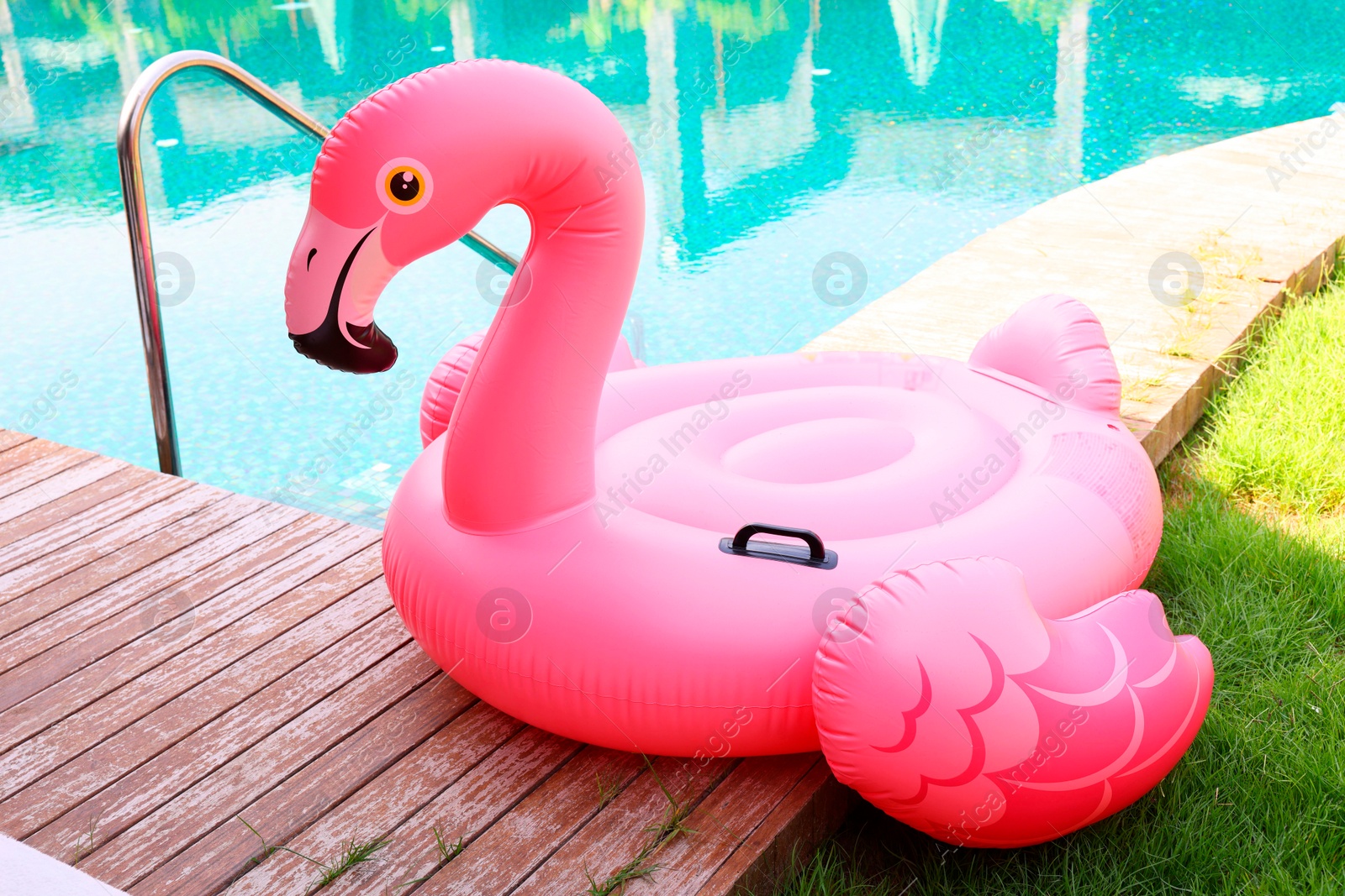 Photo of Float in shape of flamingo on wooden deck near swimming pool at luxury resort