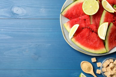 Cut juicy watermelon served with lime and sugar on blue wooden table, flat lay. Space for text