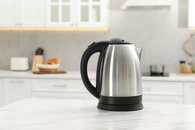 Photo of Modern electric kettle on table in kitchen. Space for text