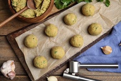 Photo of Raw falafel balls and ingredients on wooden table, flat lay