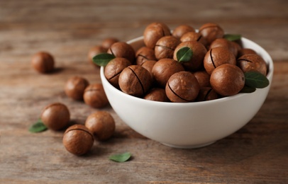 Photo of Bowl with organic Macadamia nuts and space for text on wooden background