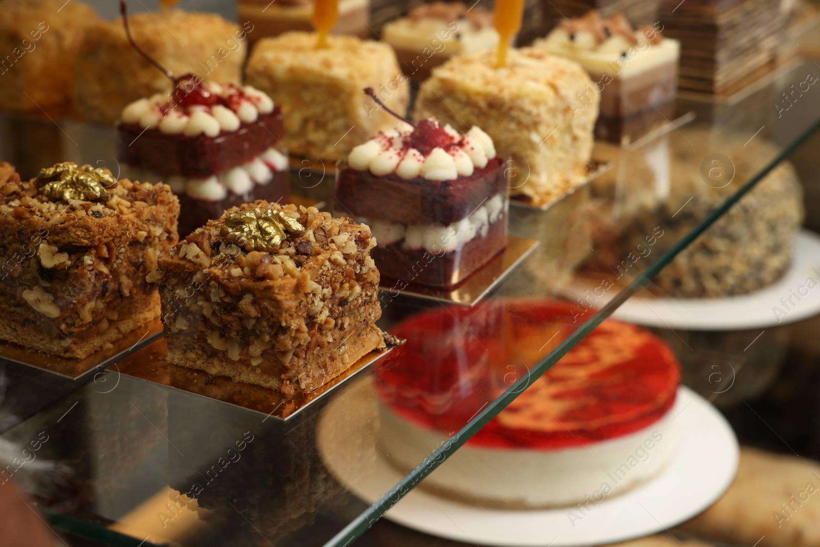 Photo of Showcase with different tasty desserts in store, closeup