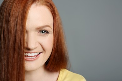 Photo of Candid portrait of happy young woman with charming smile and gorgeous red hair on grey background, closeup. Space for text