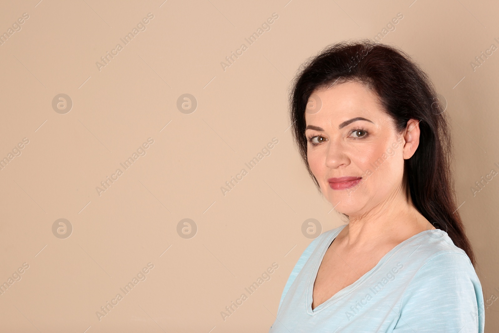 Photo of Portrait of charming mature woman with healthy beautiful face skin and natural makeup on beige background, space for text