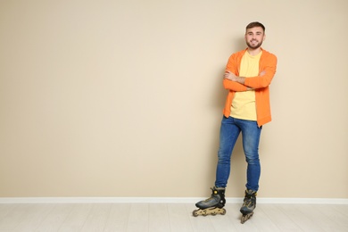 Photo of Full length portrait of young man with roller skates near color wall. Space for text