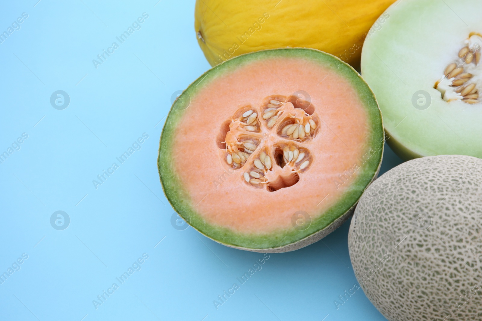 Photo of Different tasty ripe melons on turquoise background, closeup. Space for text