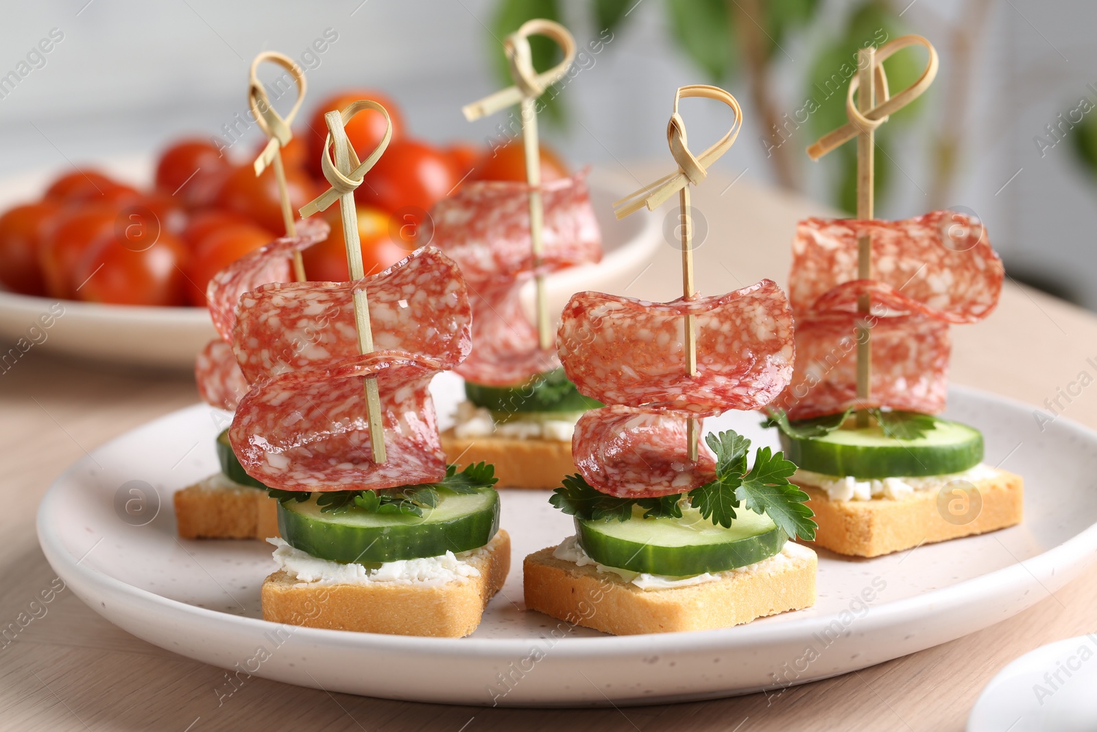 Photo of Tasty canapes with salami, cucumber and cream cheese on light table, closeup