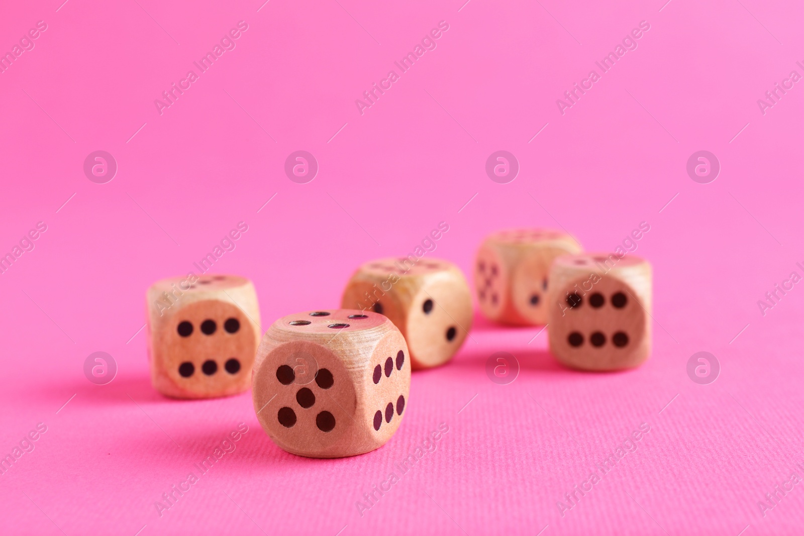 Photo of Many wooden game dices on pink background, closeup