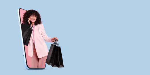 Online shopping. Happy woman with paper bags looking out from smartphone on light blue background, space for text. Banner design