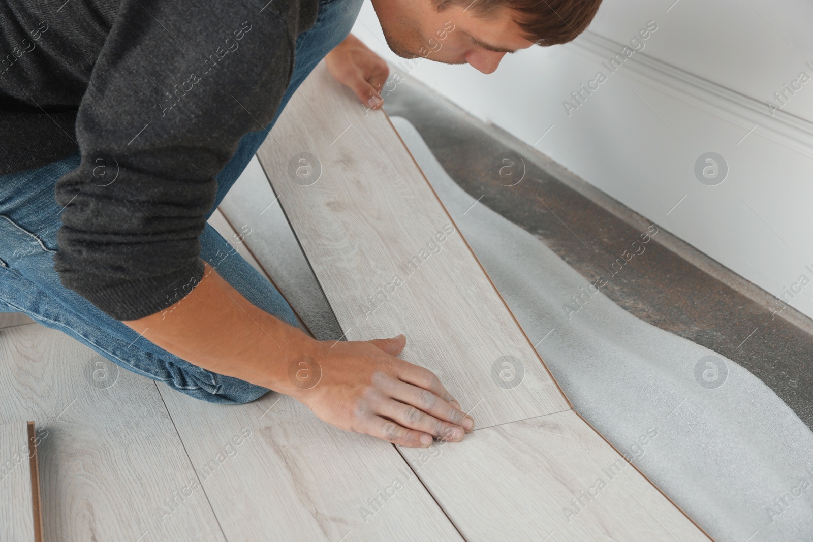 Photo of Worker installing new laminate flooring in room, closeup