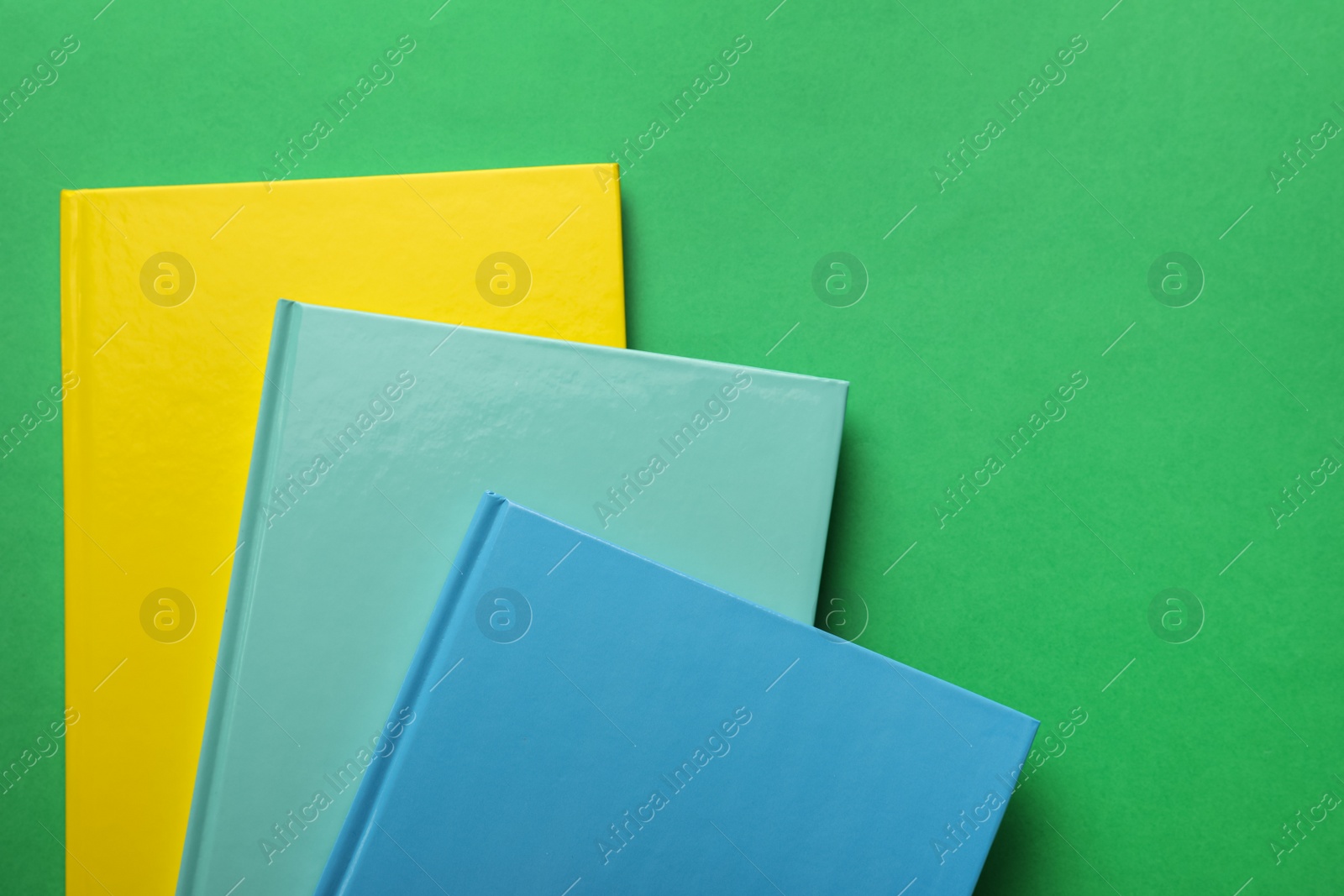 Photo of Stylish colorful planners on green background, top view