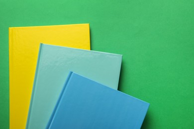 Photo of Stylish colorful planners on green background, top view