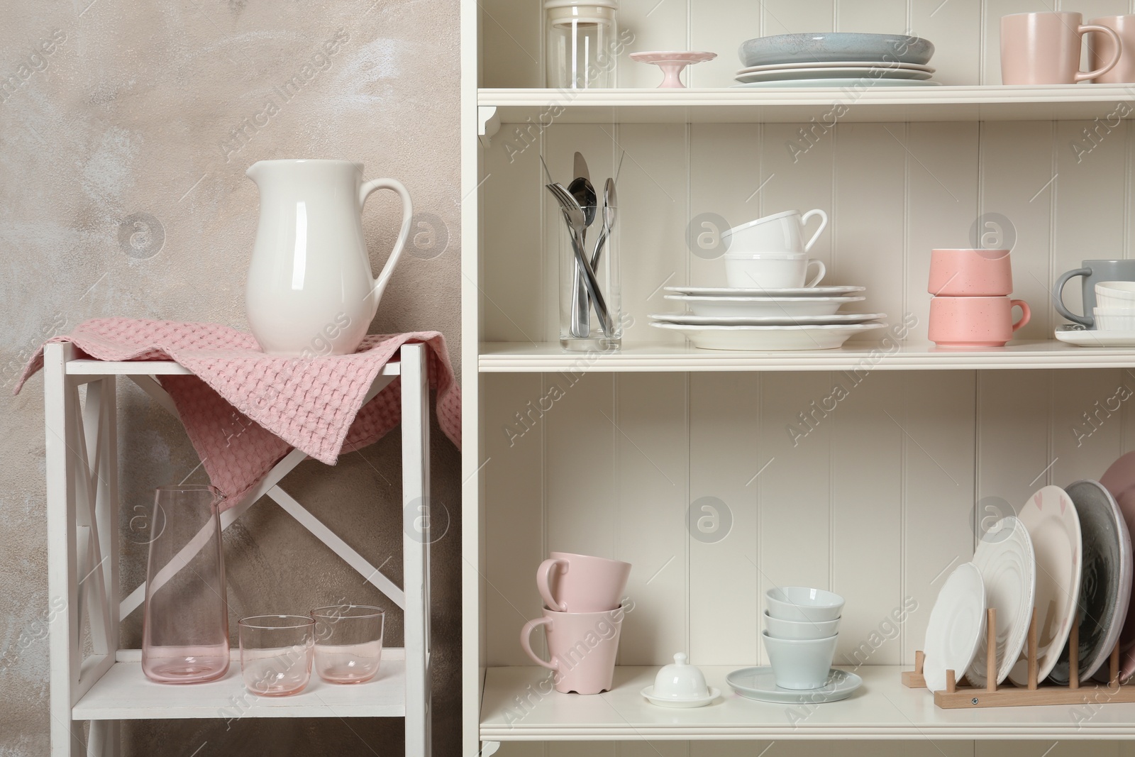 Photo of White shelving unit with set of dishware near wall